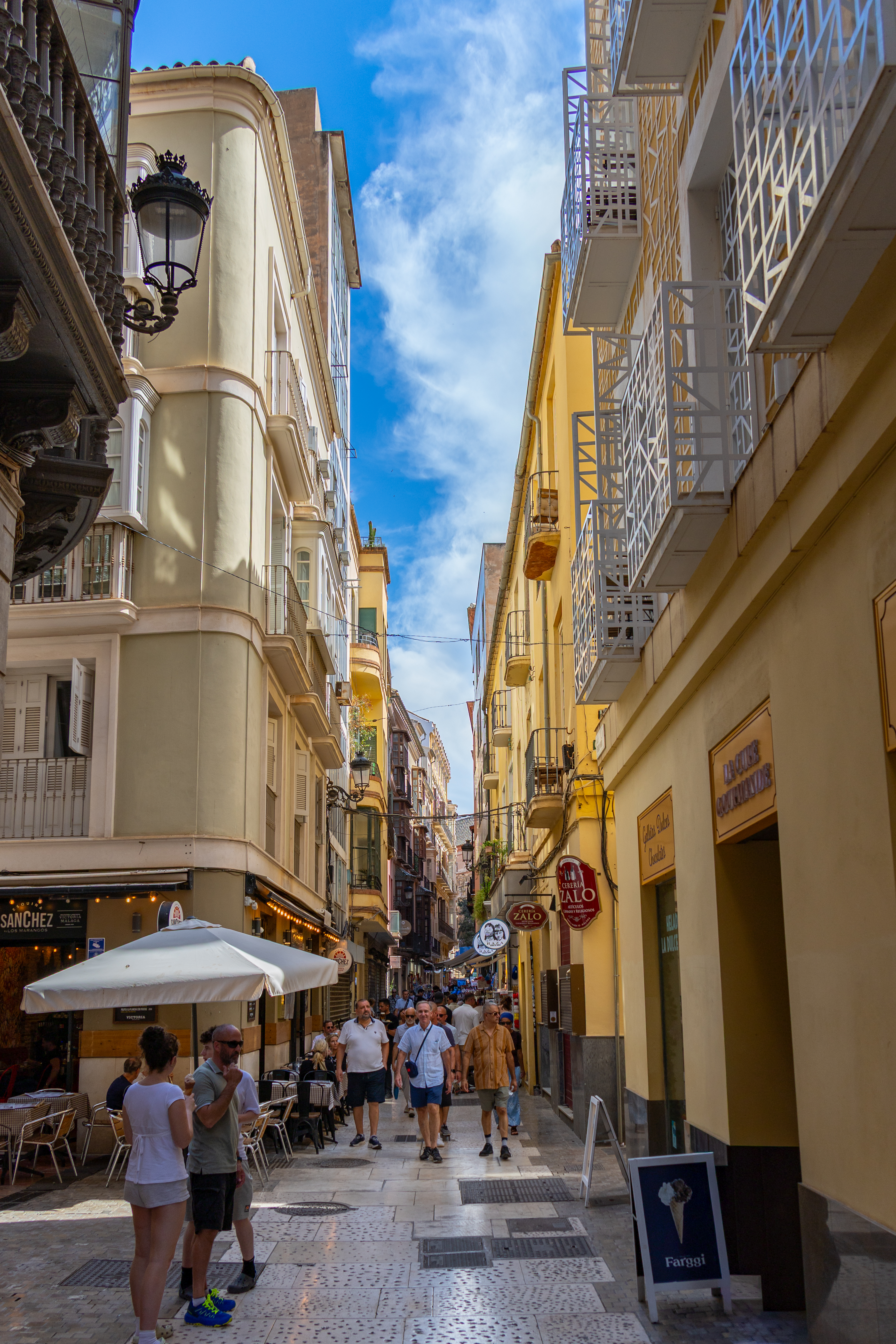 Belebte Altstadtgasse in Malaga mit gelben Fassaden