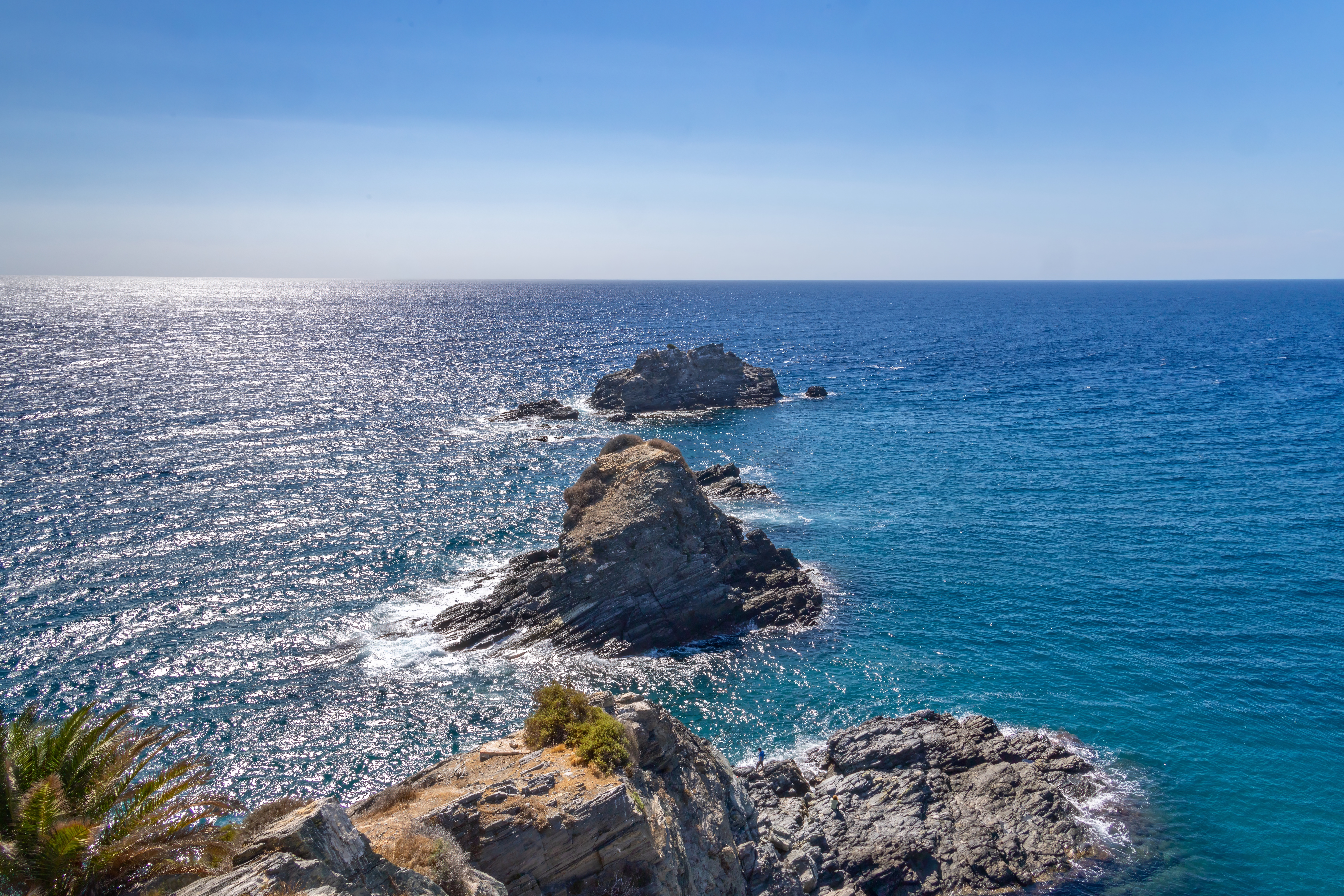 Felsen im glitzernden blauen Meer vor einer Küste
